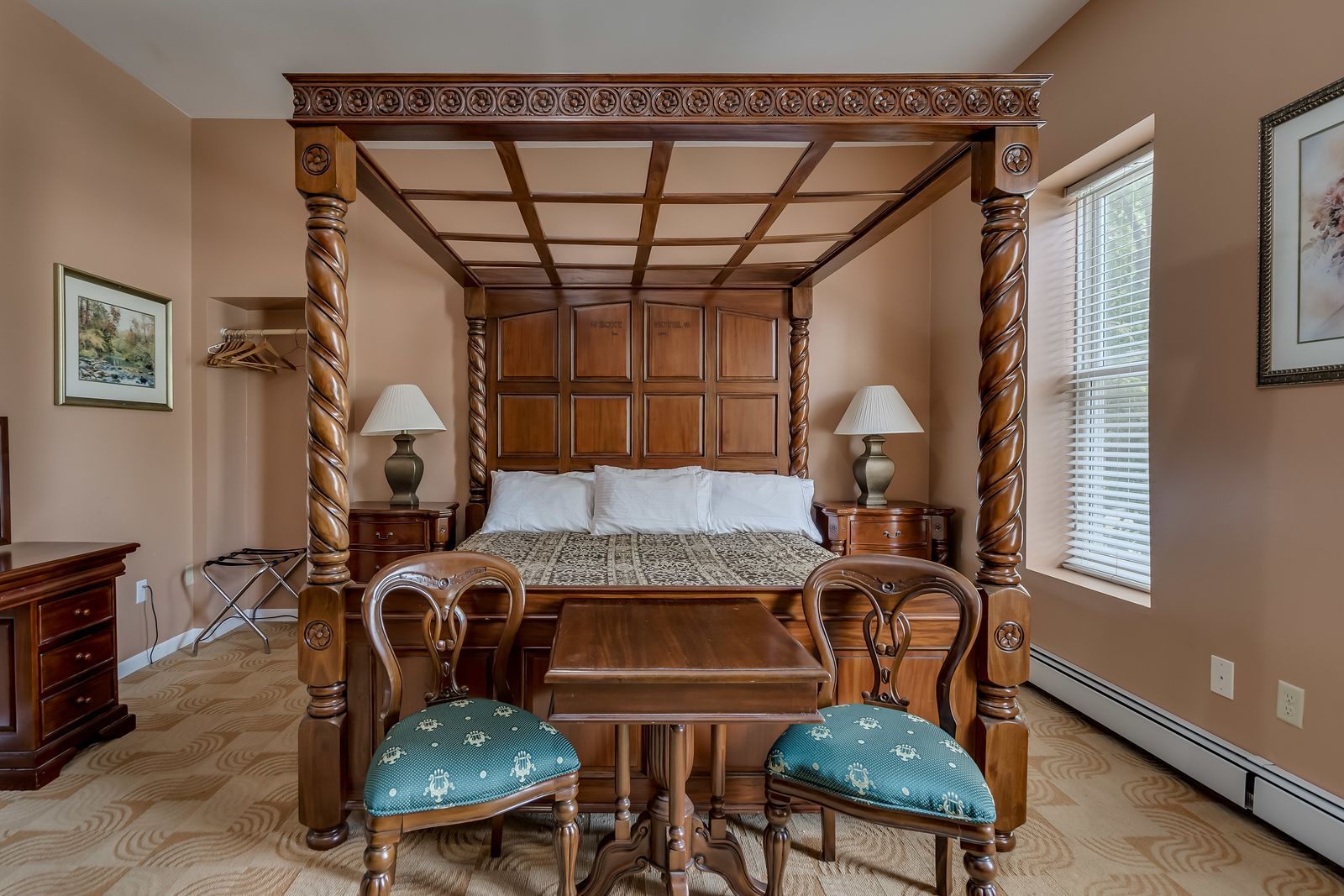 A bedroom with a four poster bed and a table and chairs