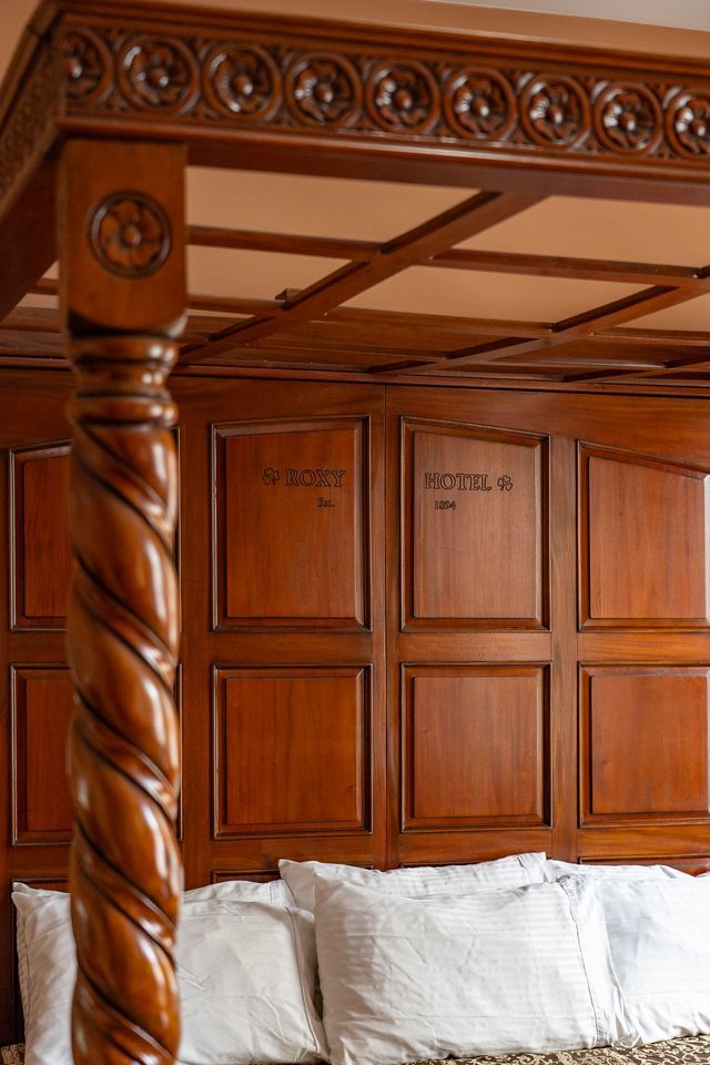 A bed with a wooden canopy and white pillows