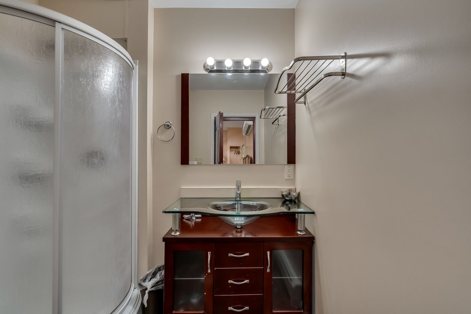 A bathroom with a sink , mirror and shower.