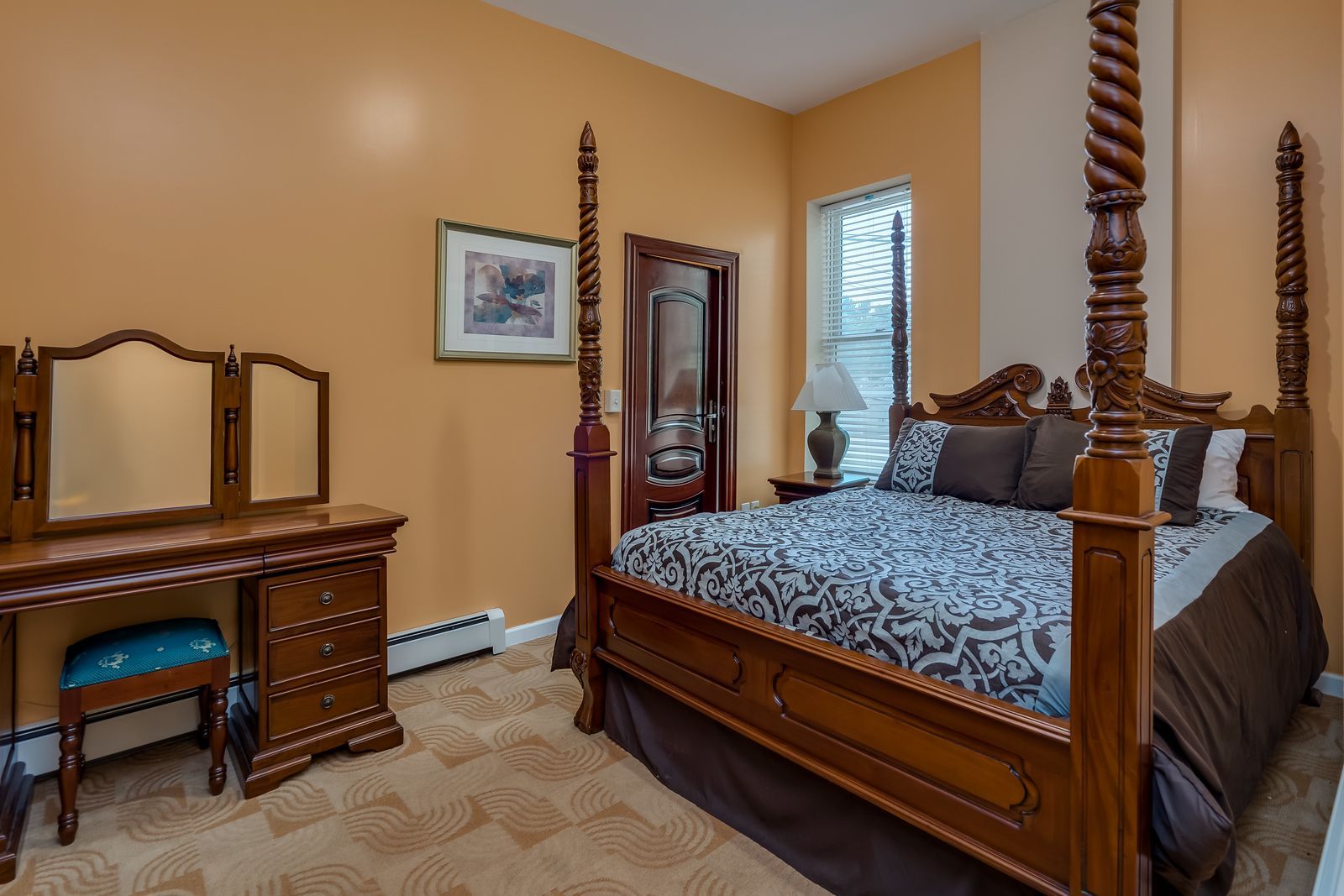 A bedroom with a four poster bed , dresser and mirror.