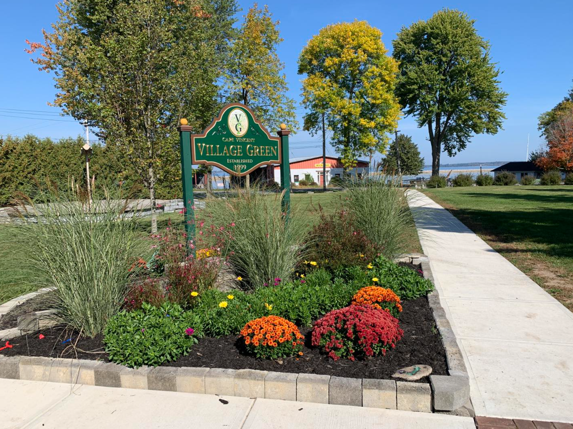 There is a sign in the middle of a garden with flowers.