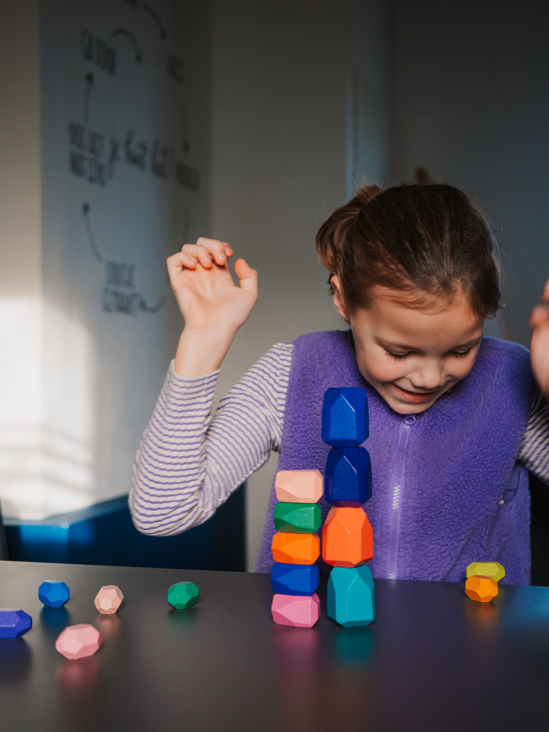 Een klein meisje zit aan een tafel en speelt met blokken.