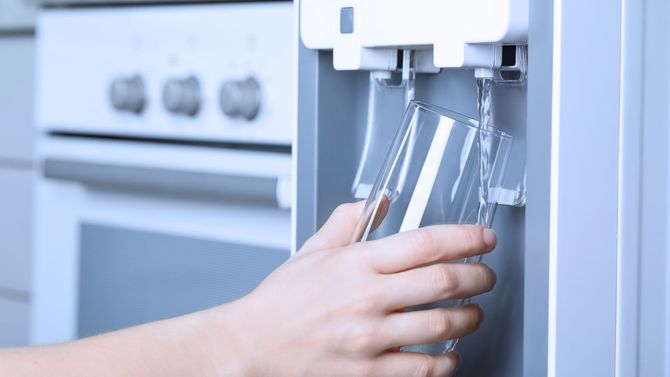 Hand filling a clear glass from a fresh, spring water dispenser - Indian Peaks Spring Water