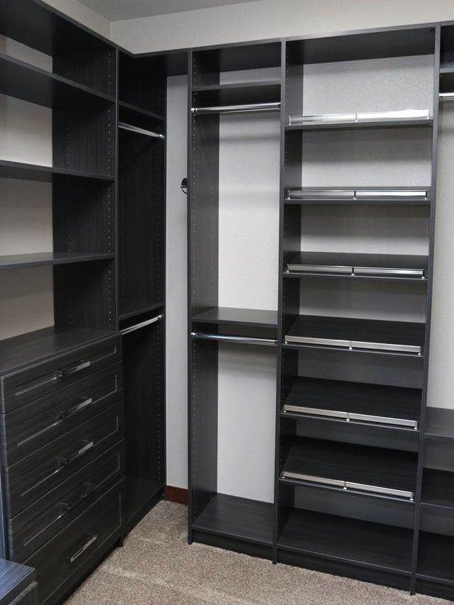A dark wood walk-in closet with shelves, a hanging rod, and a bank of drawers.