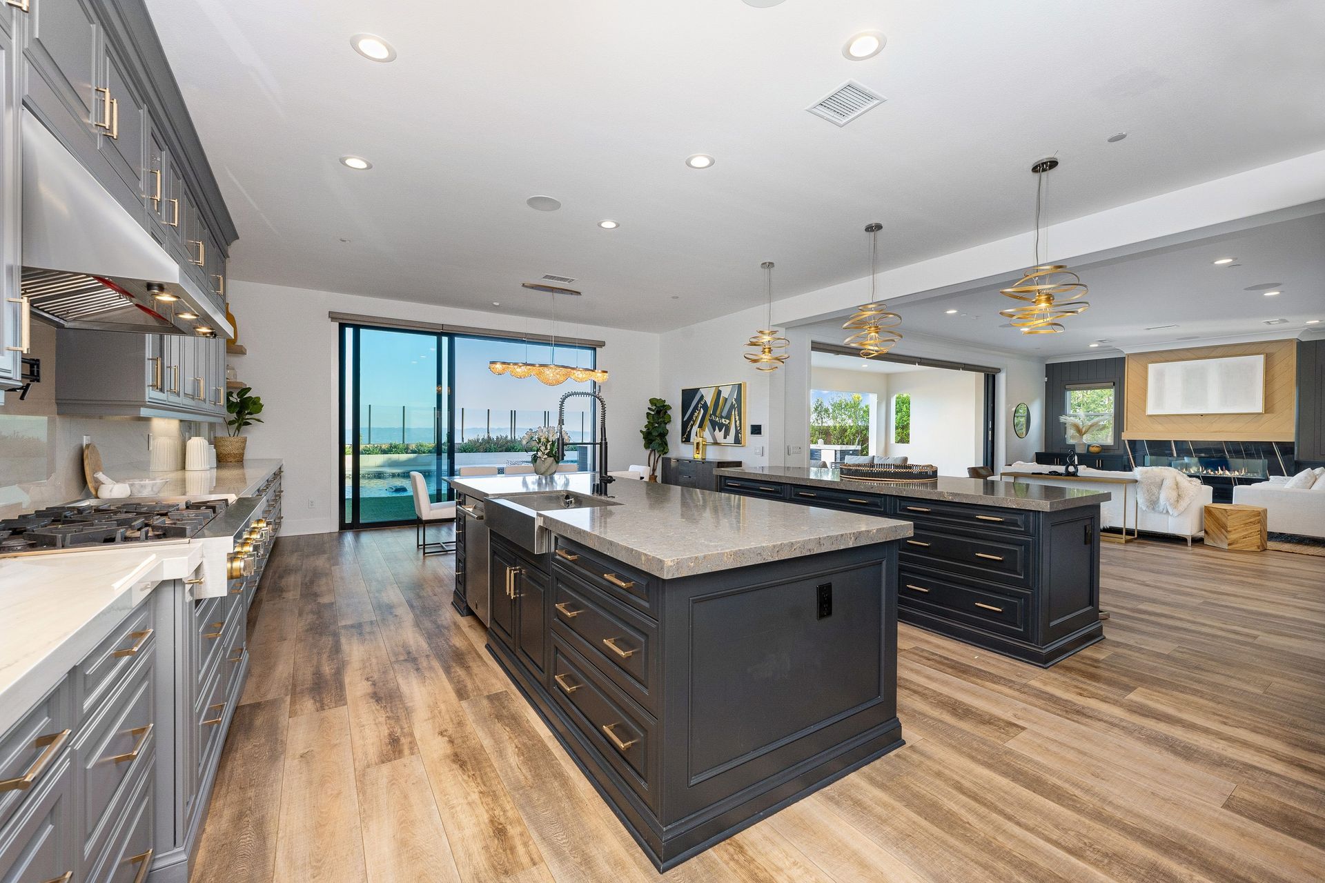 Modern open-concept kitchen with dark island, gray cabinets, and large sliding glass doors to a patio.