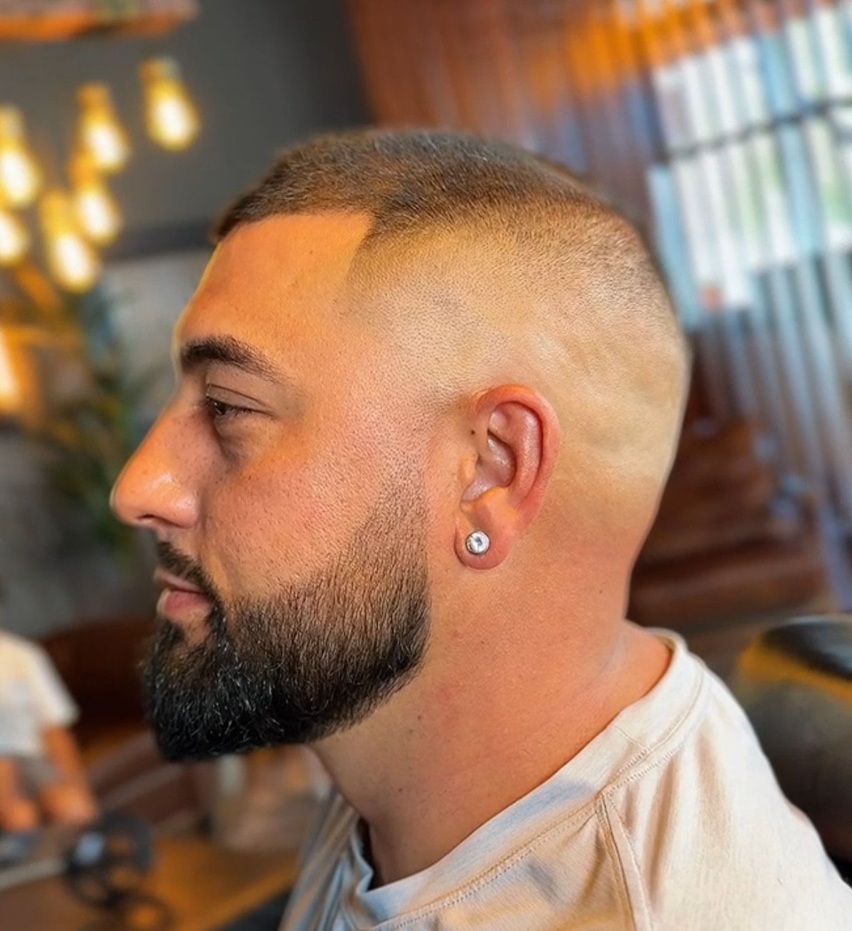 Man with a faded haircut and beard in a barber shop setting.