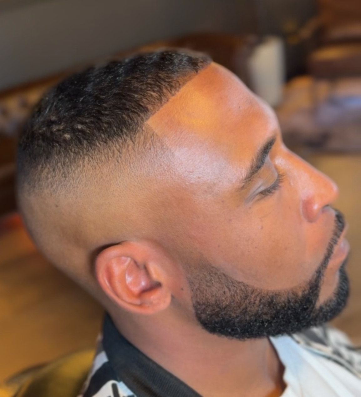 Man with a faded haircut and beard. He has a sharp line-up with a groomed beard.