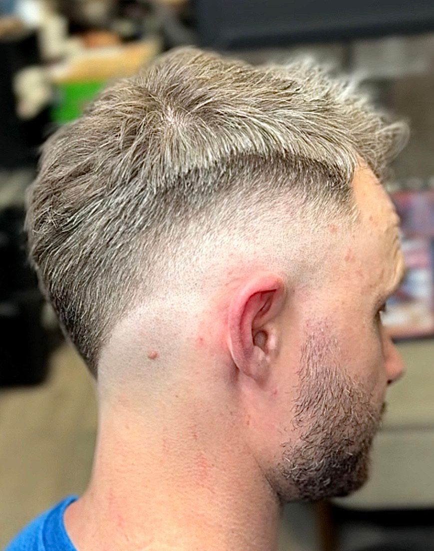 Man with a faded haircut, light hair, and close-shaved sides, profile view.