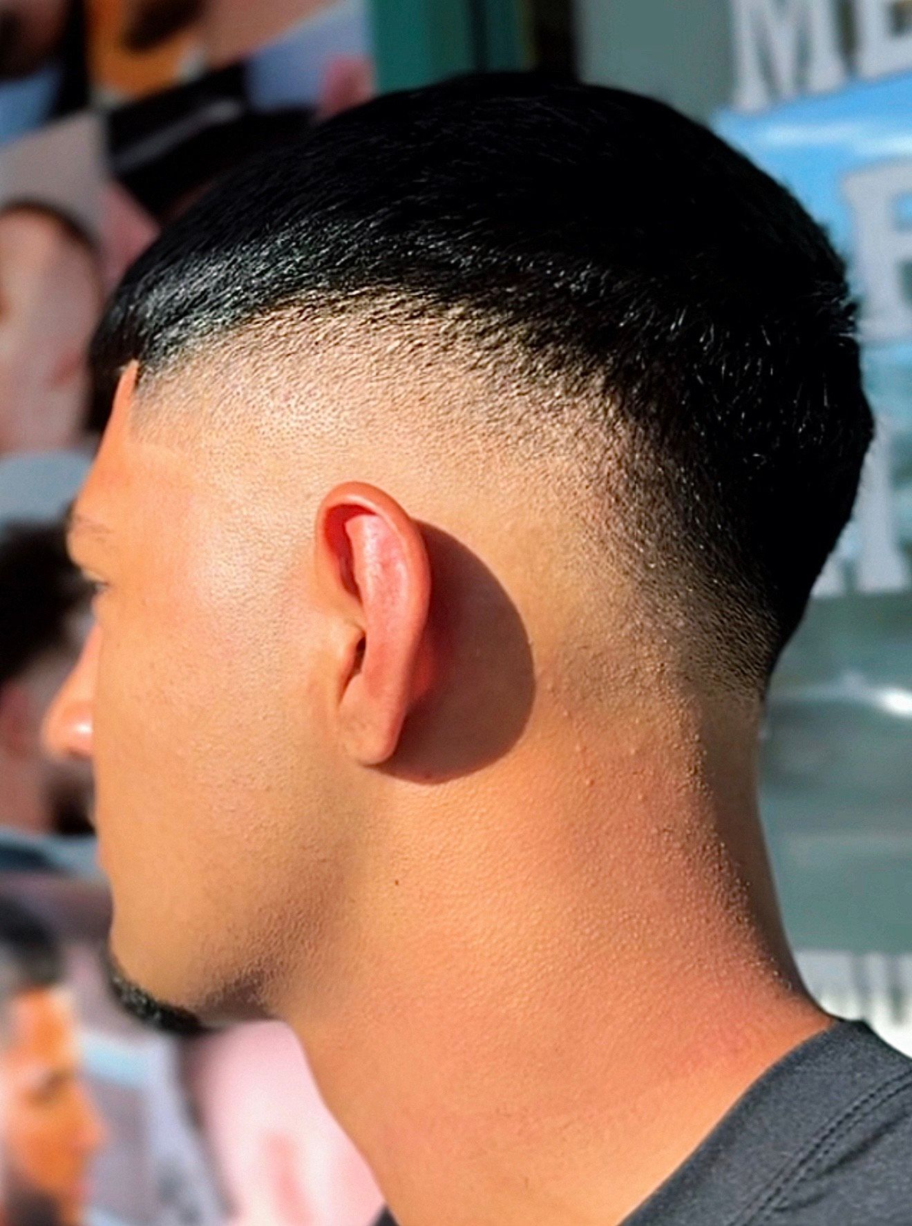 Man with a faded haircut, dark hair on top, side profile.