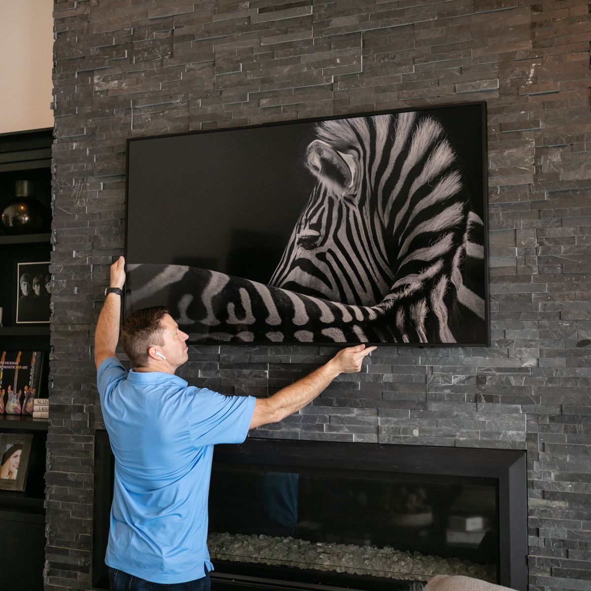 A man is hanging a picture of a zebra on the wall