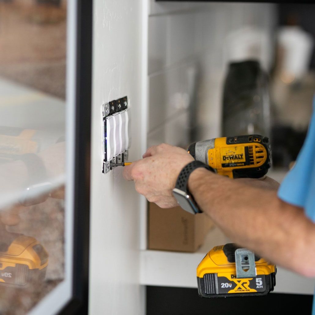 A man is using a dewalt cordless drill to install a light switch