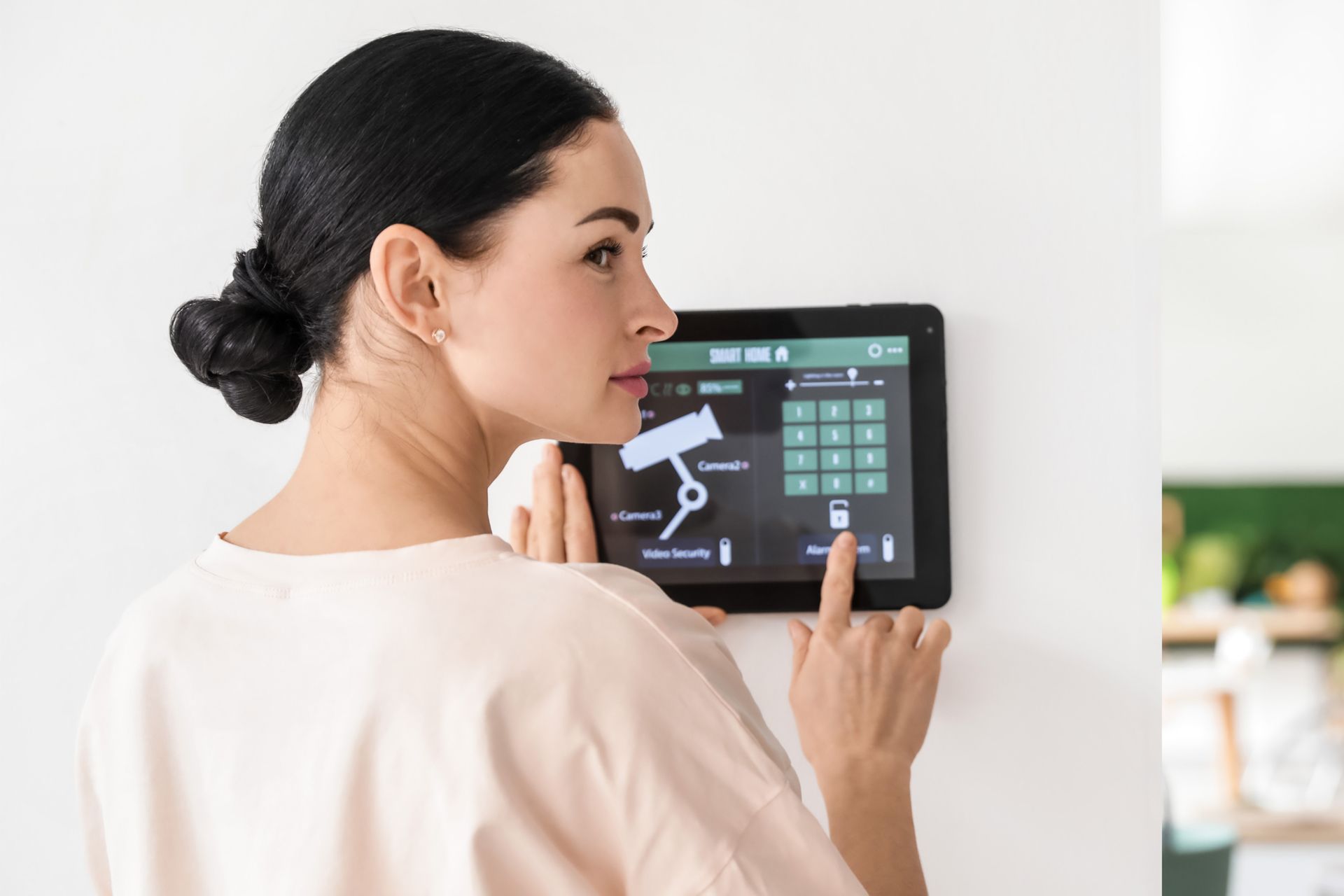 A woman is using a tablet to control a security system