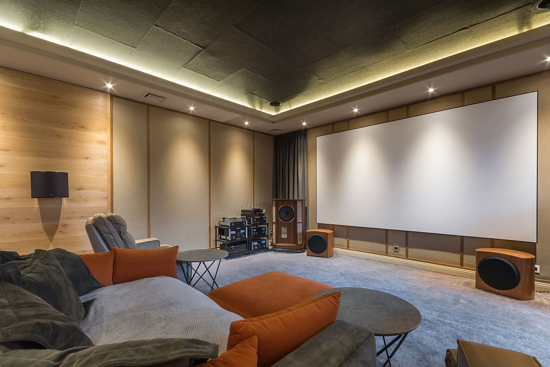 A home theater with a couch,  chairs, speakers and a large screen