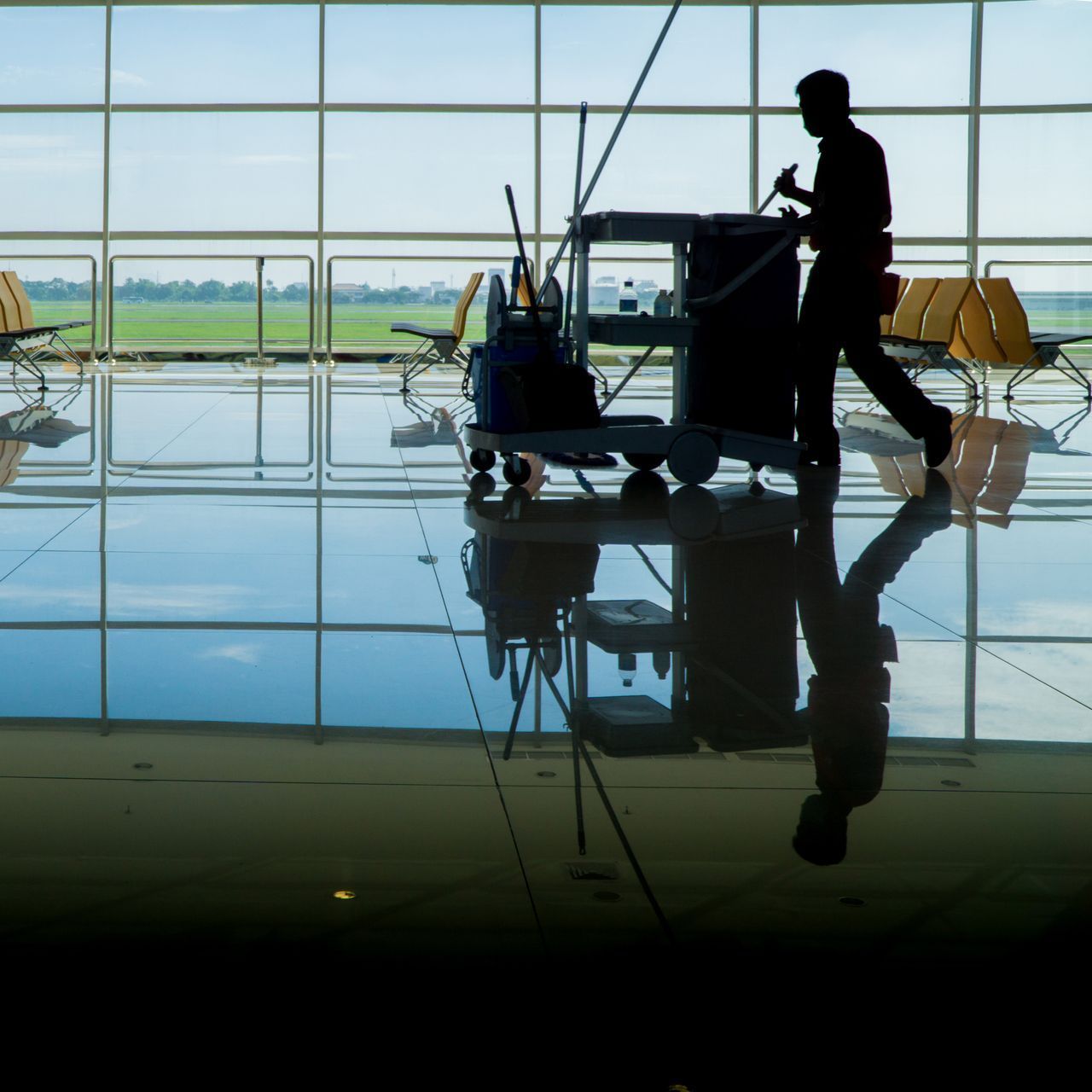 a silhouette of a man cleaning a floor with a mop