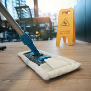 a mop is on the floor in front of a caution wet floor sign