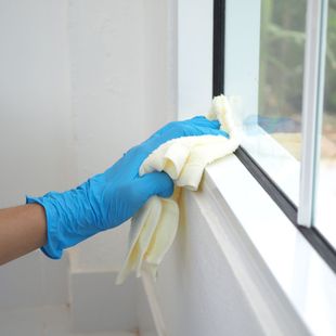 a person wearing blue gloves is cleaning a window