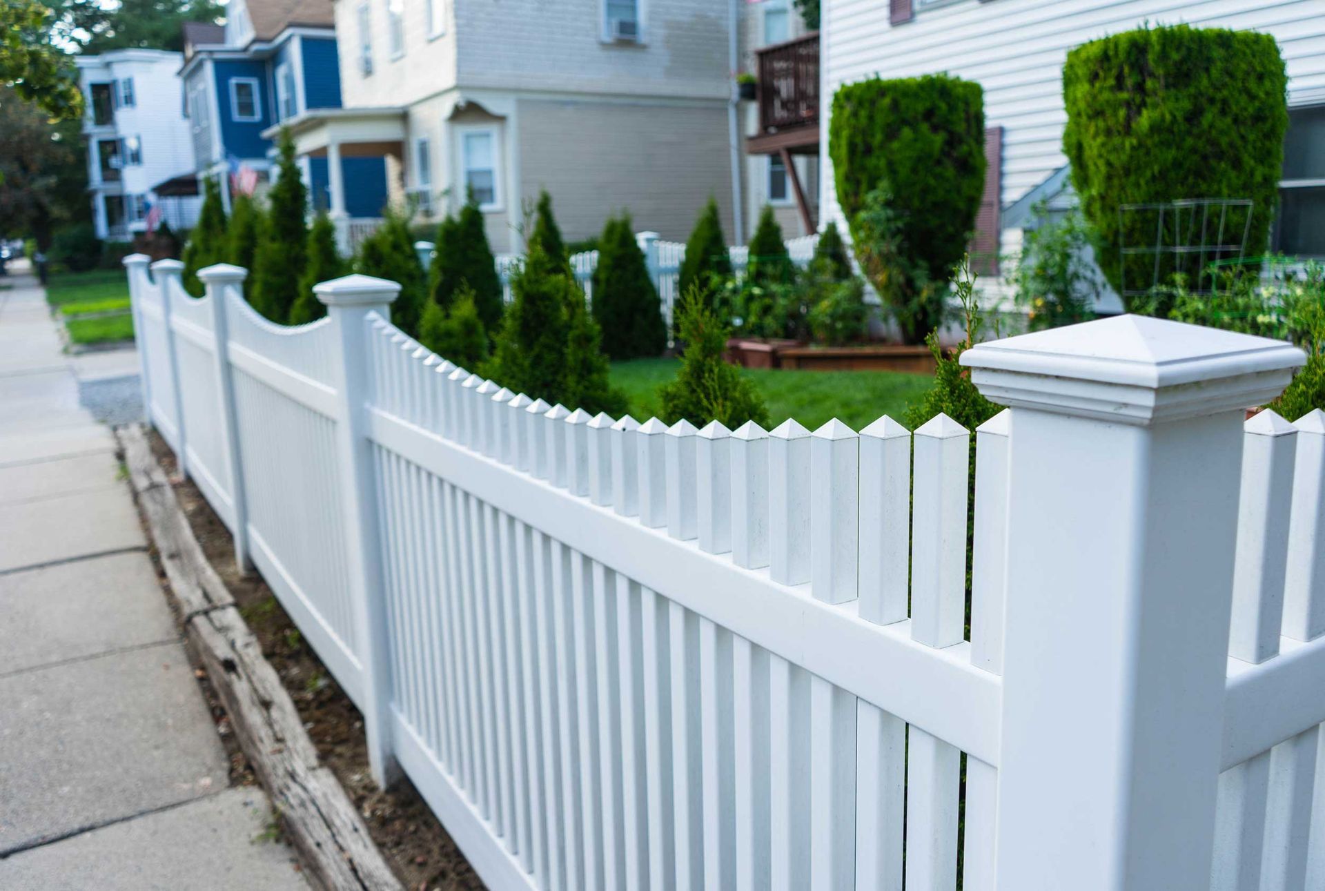 A white picket fence, installed by a professional residential fence company, lines a suburban yard.