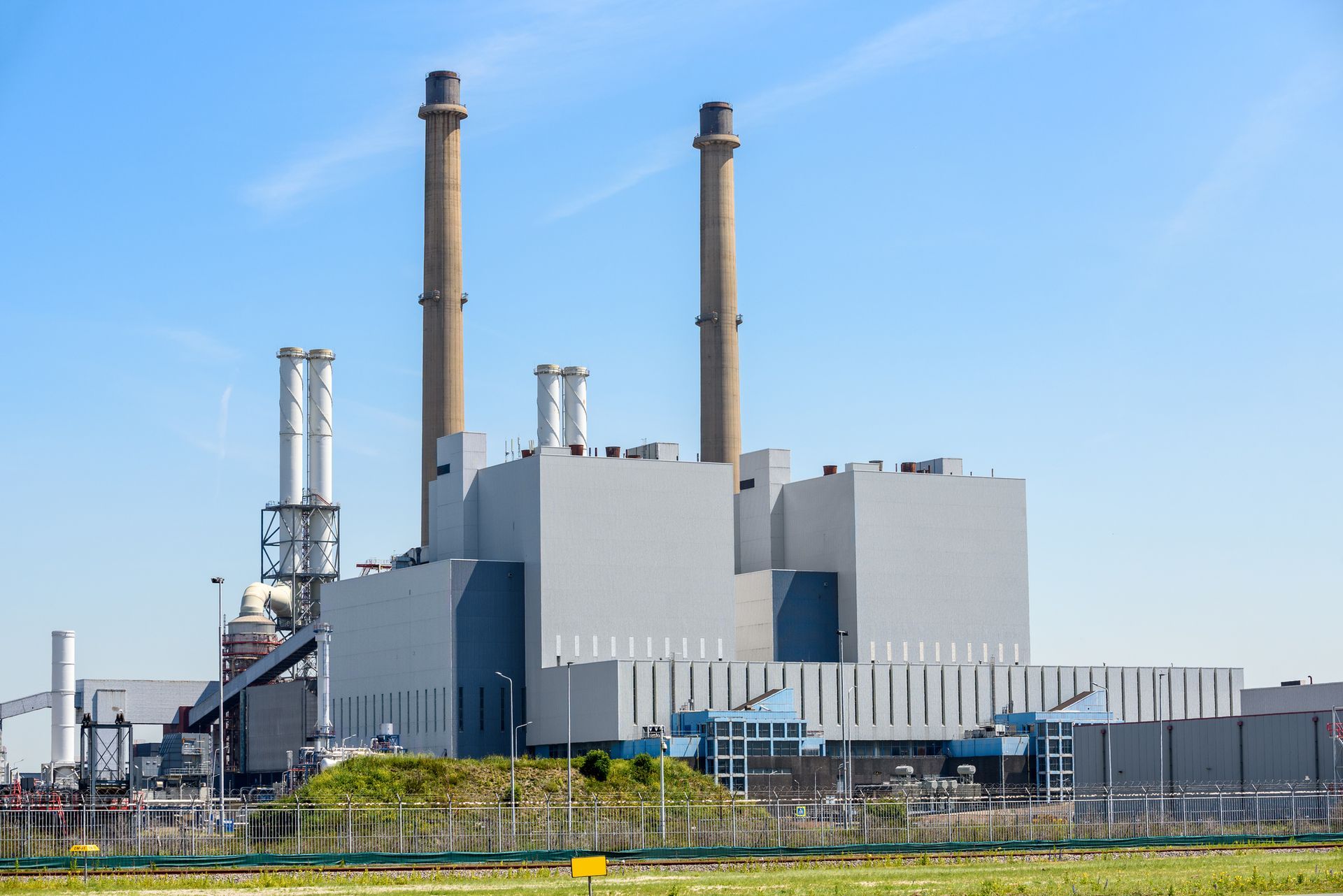 Power plant with tall smokestacks against a clear blue sky.