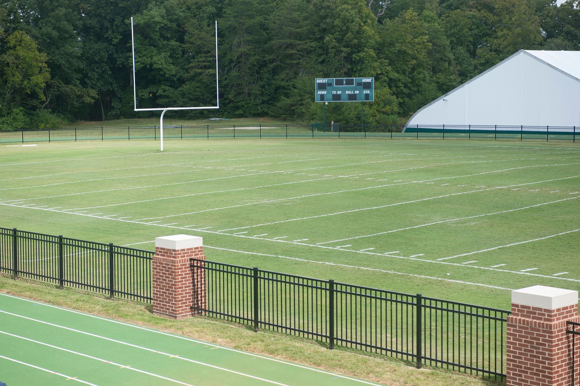 Football field with goalpost, scoreboard, and fencing.
