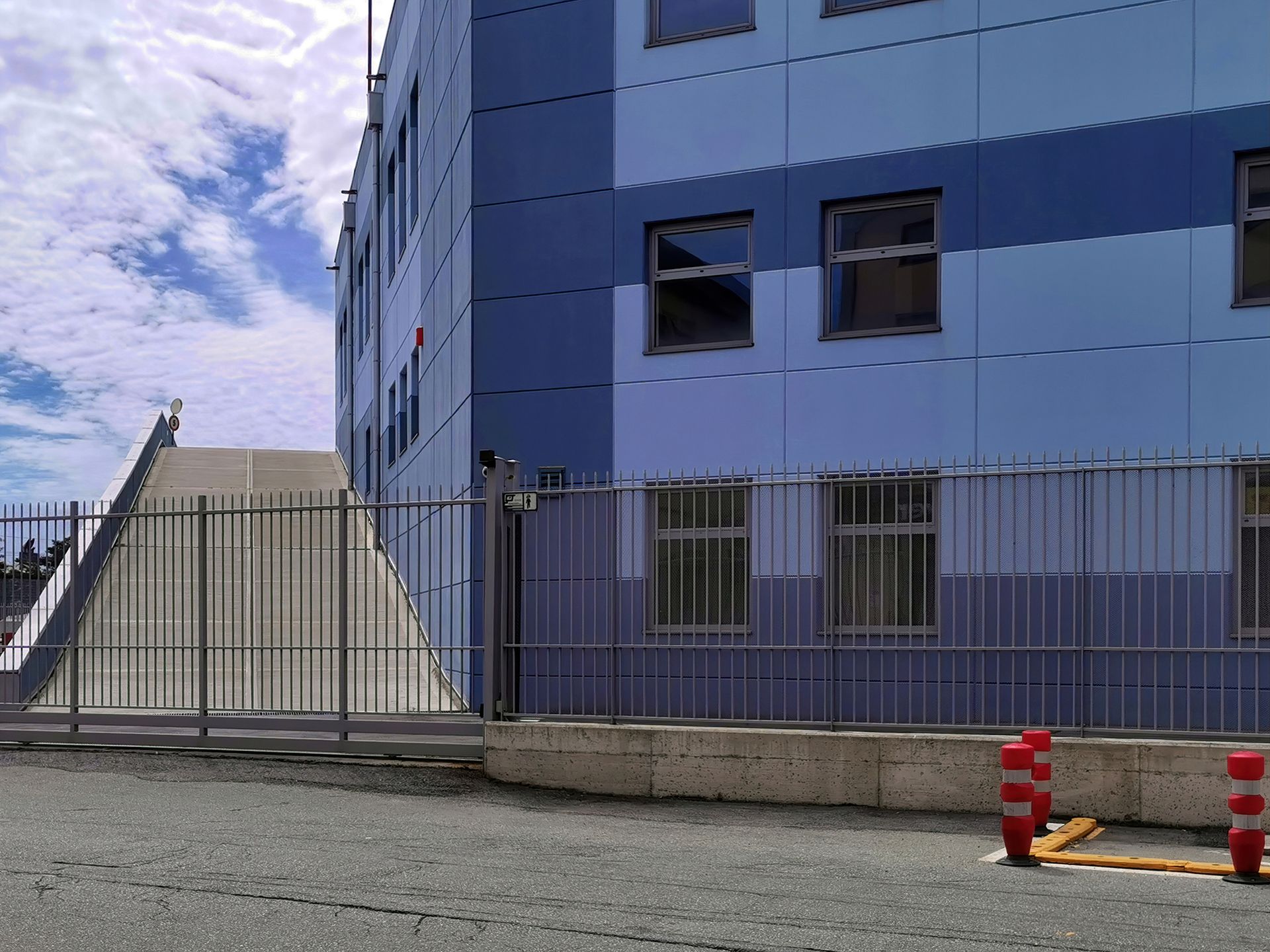 Blue building exterior with ramp and security fence.