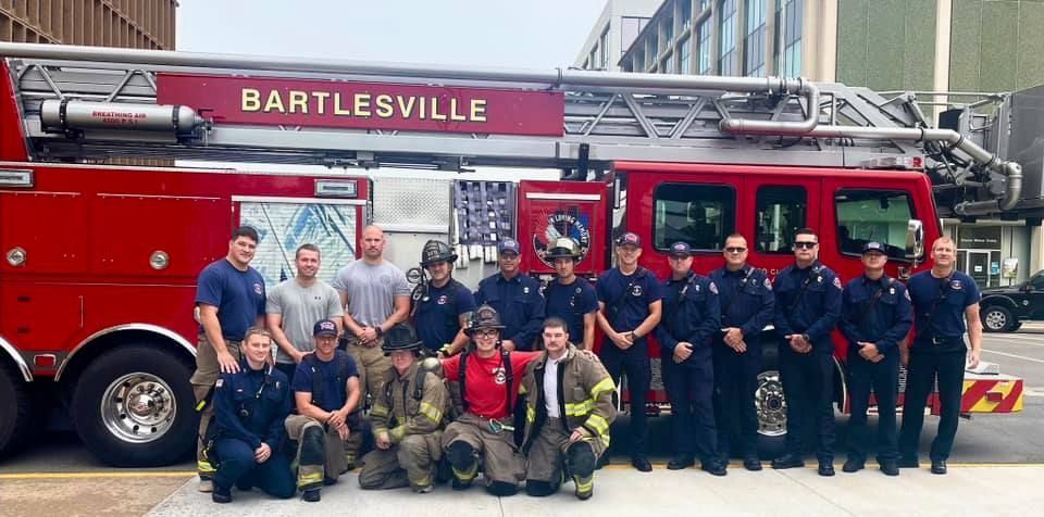 A group of firefighters are posing for a picture in front of a fire truck.