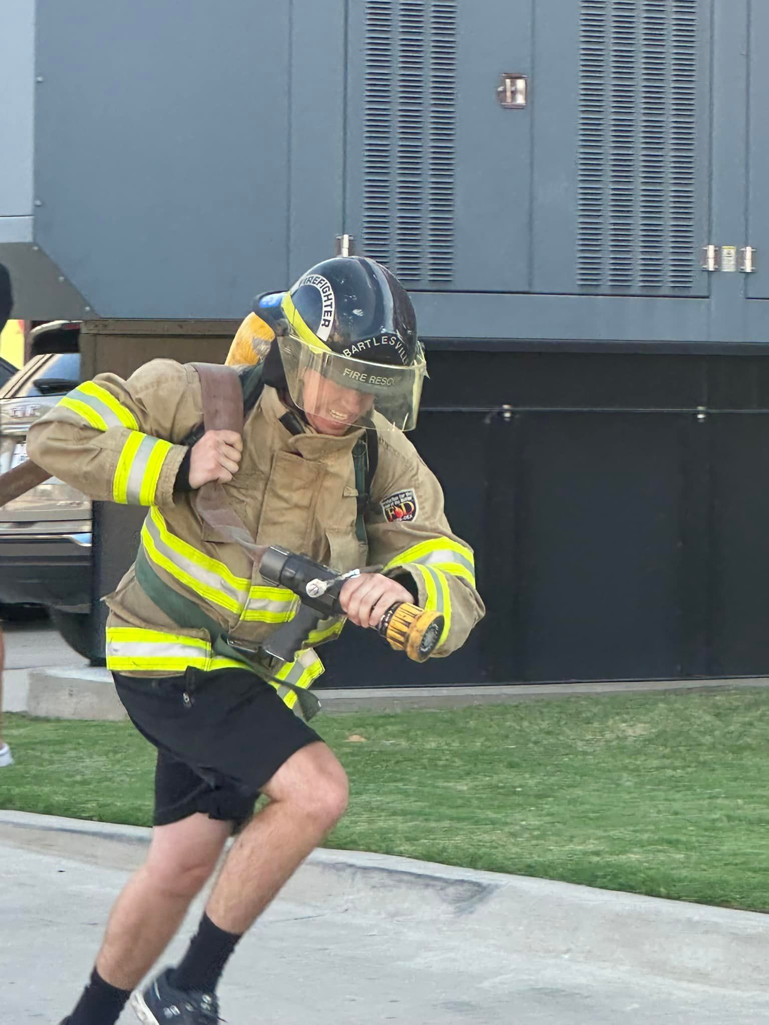 A man in a fireman 's uniform is holding a hose