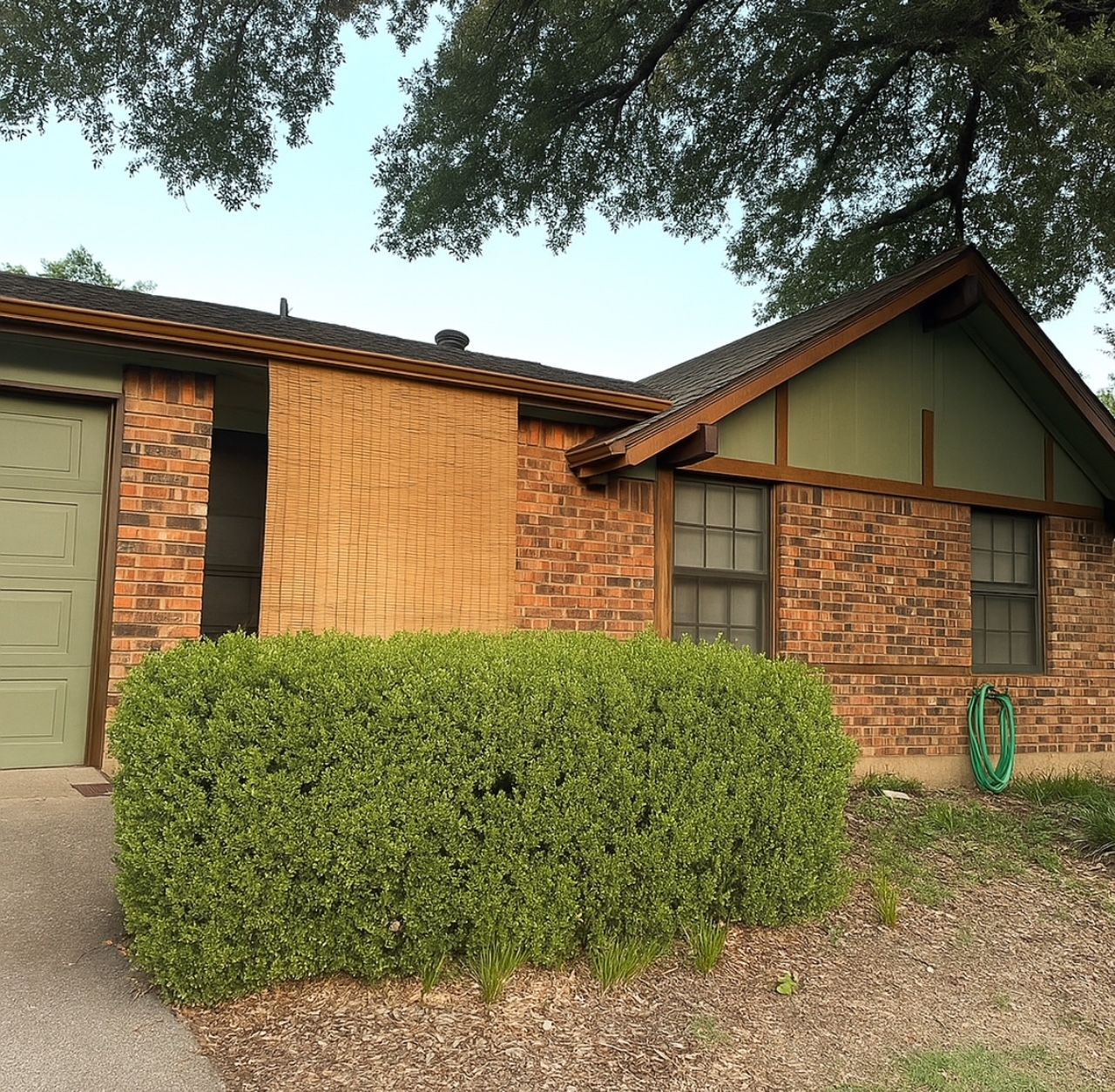 Brick house with green trim, a bush in front, and a tree overhead.