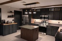 Green kitchen with dark hexagon floor, stainless steel appliances, and wooden countertops.
