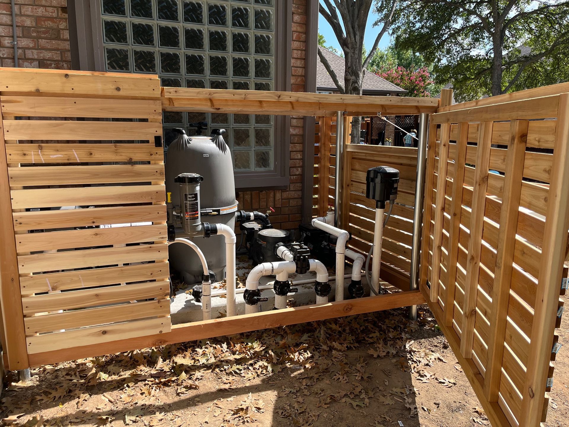 Wooden enclosure housing pool equipment. Brown, with pipes, gauges, and filtering system visible. Outdoor setting.