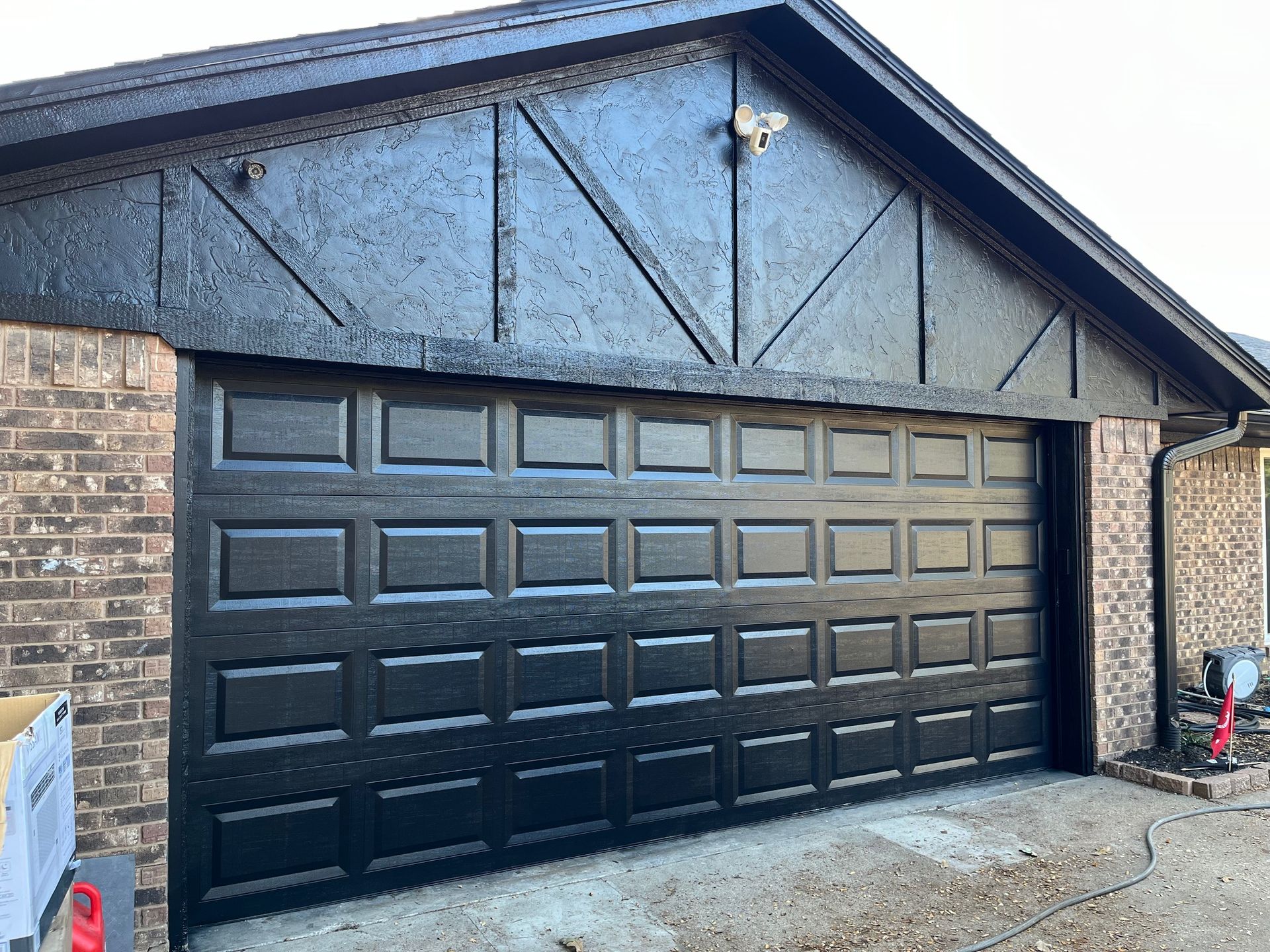 Black garage door with brick and dark trim.