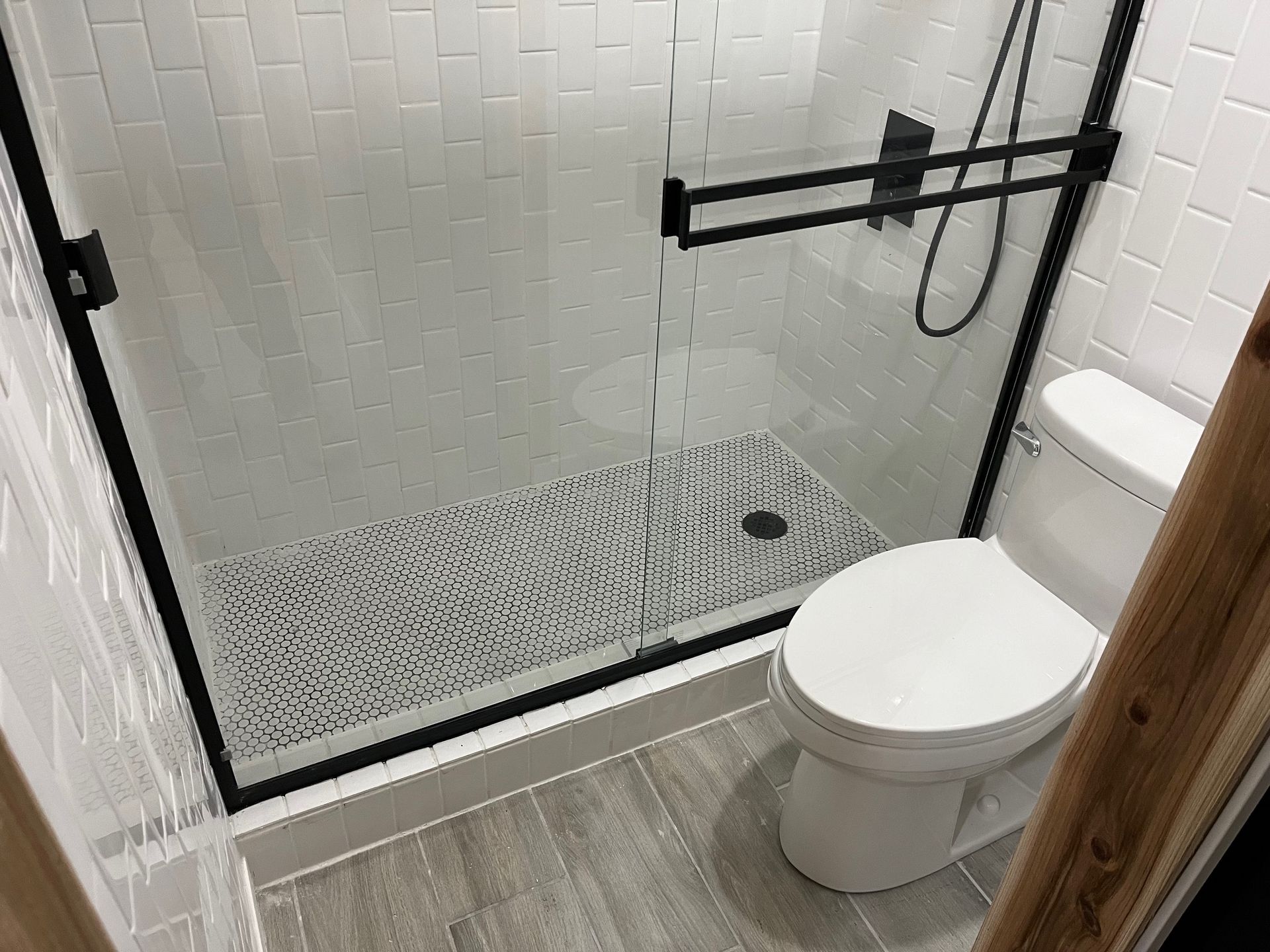Modern bathroom with a glass shower, black fixtures, and a white toilet.