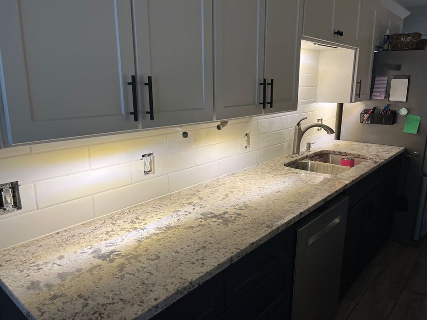 Kitchen with white cabinets, light granite countertop, and stainless steel sink.