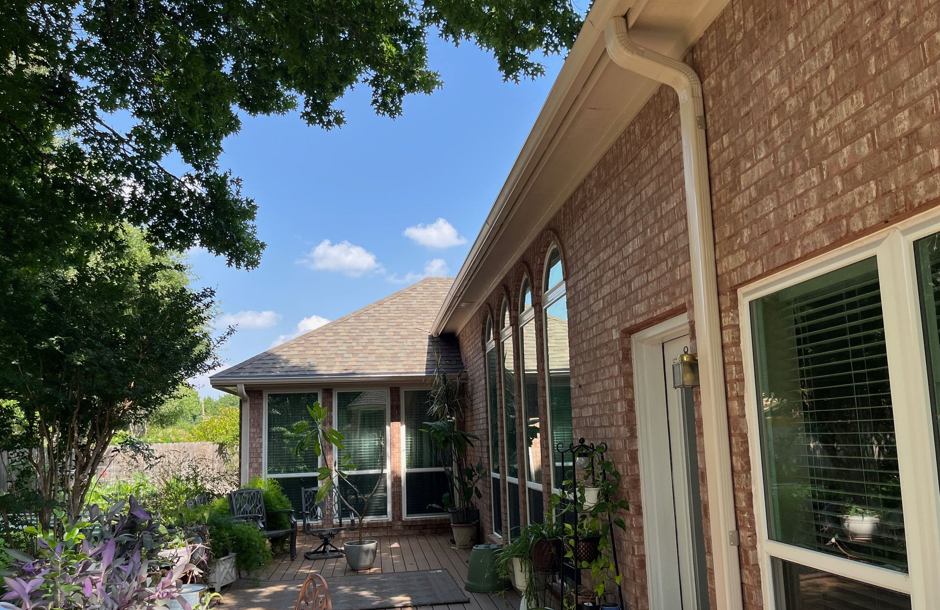 Brick house with arched windows, a doorway, and a brown roof against a blue sky.