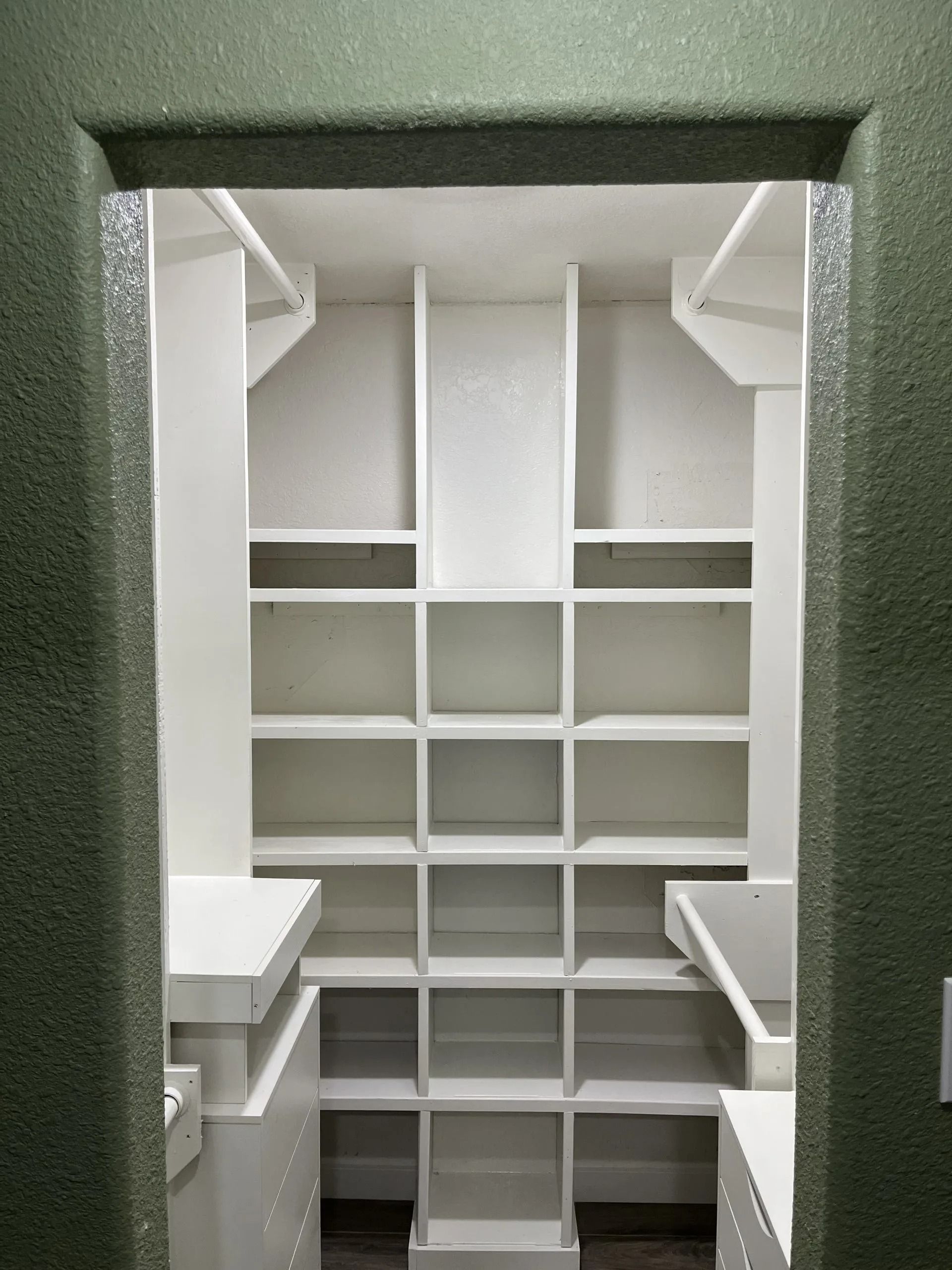 White shelving inside a storage room; green doorway frame.