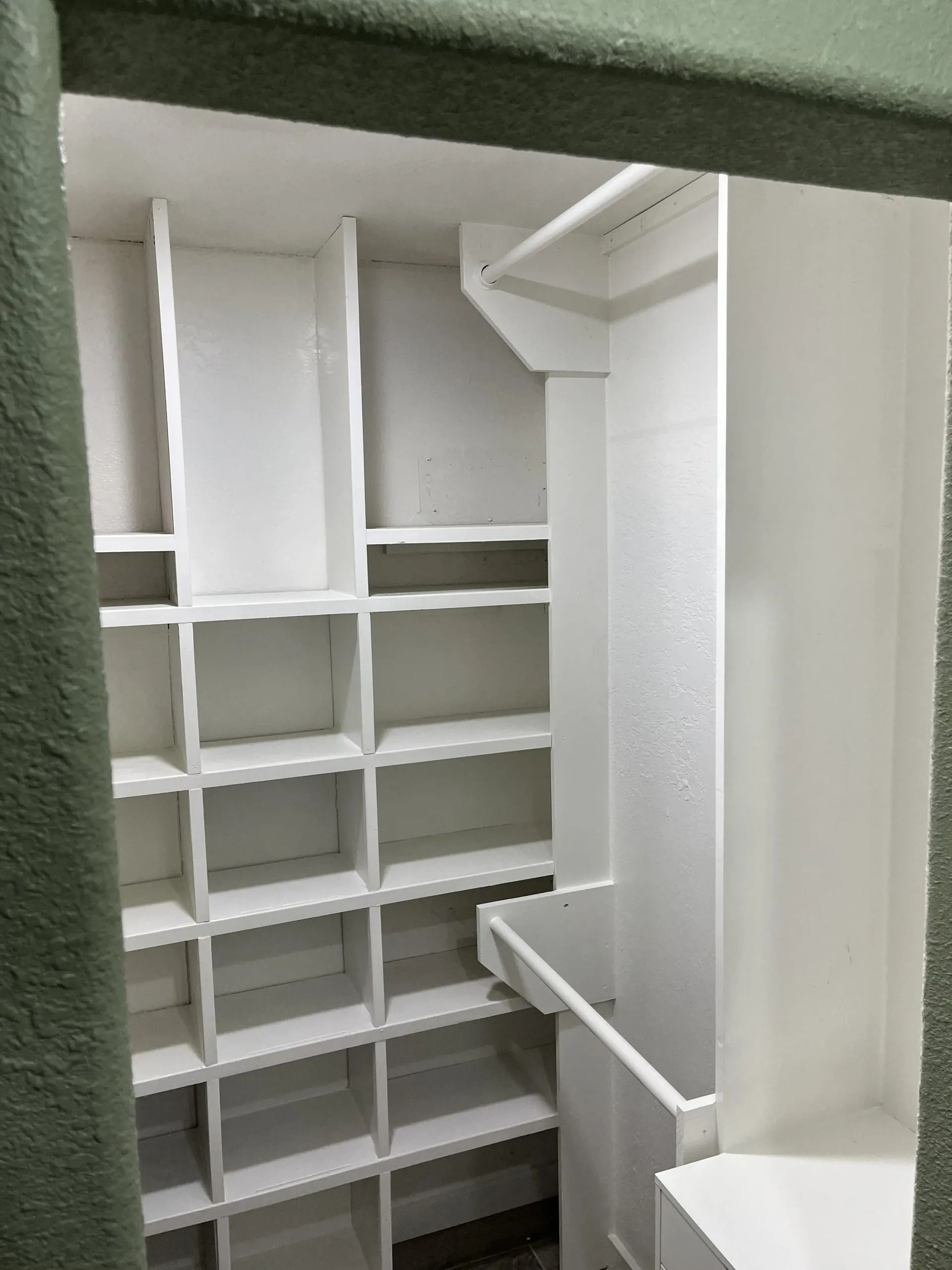 White shelving unit inside a pantry. Shelves are organized into numerous cubbies.
