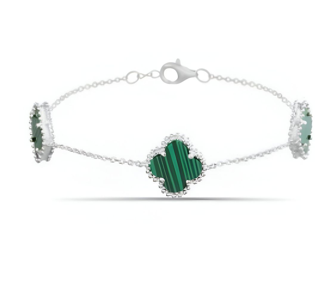 Una pulsera de plata con una piedra verde en forma de trébol.