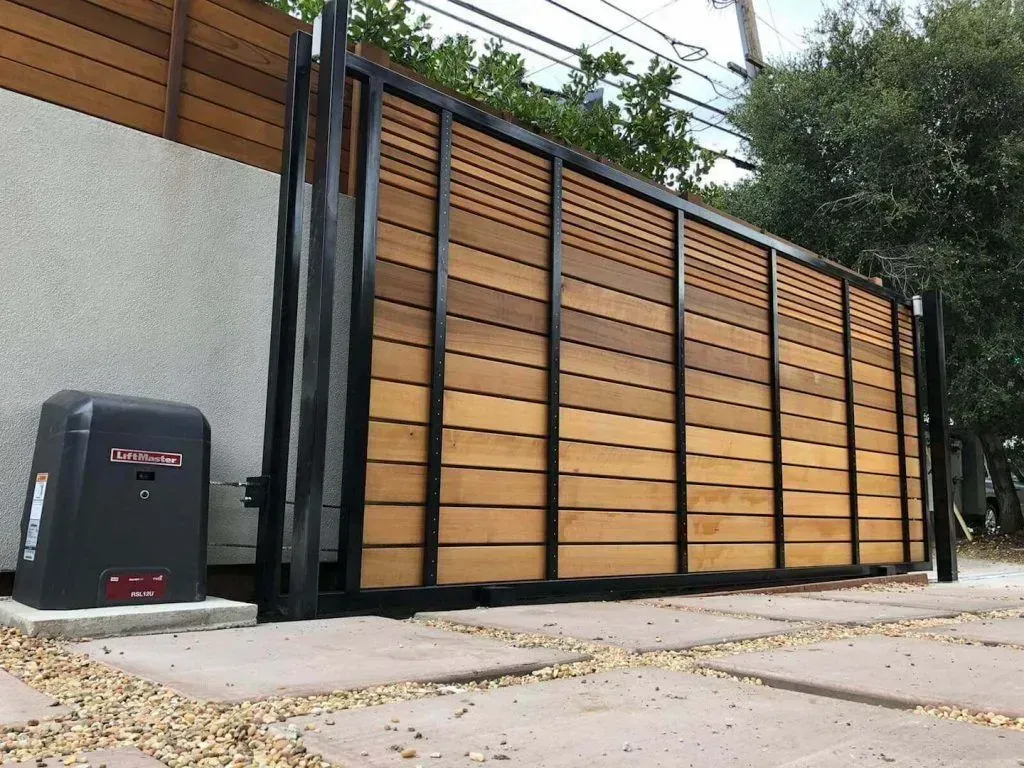 A wooden automatic gate with a black frame and a black box on the side of it featuring an expert gate installation in the North Shore and Boston by Boston Gate Operators
