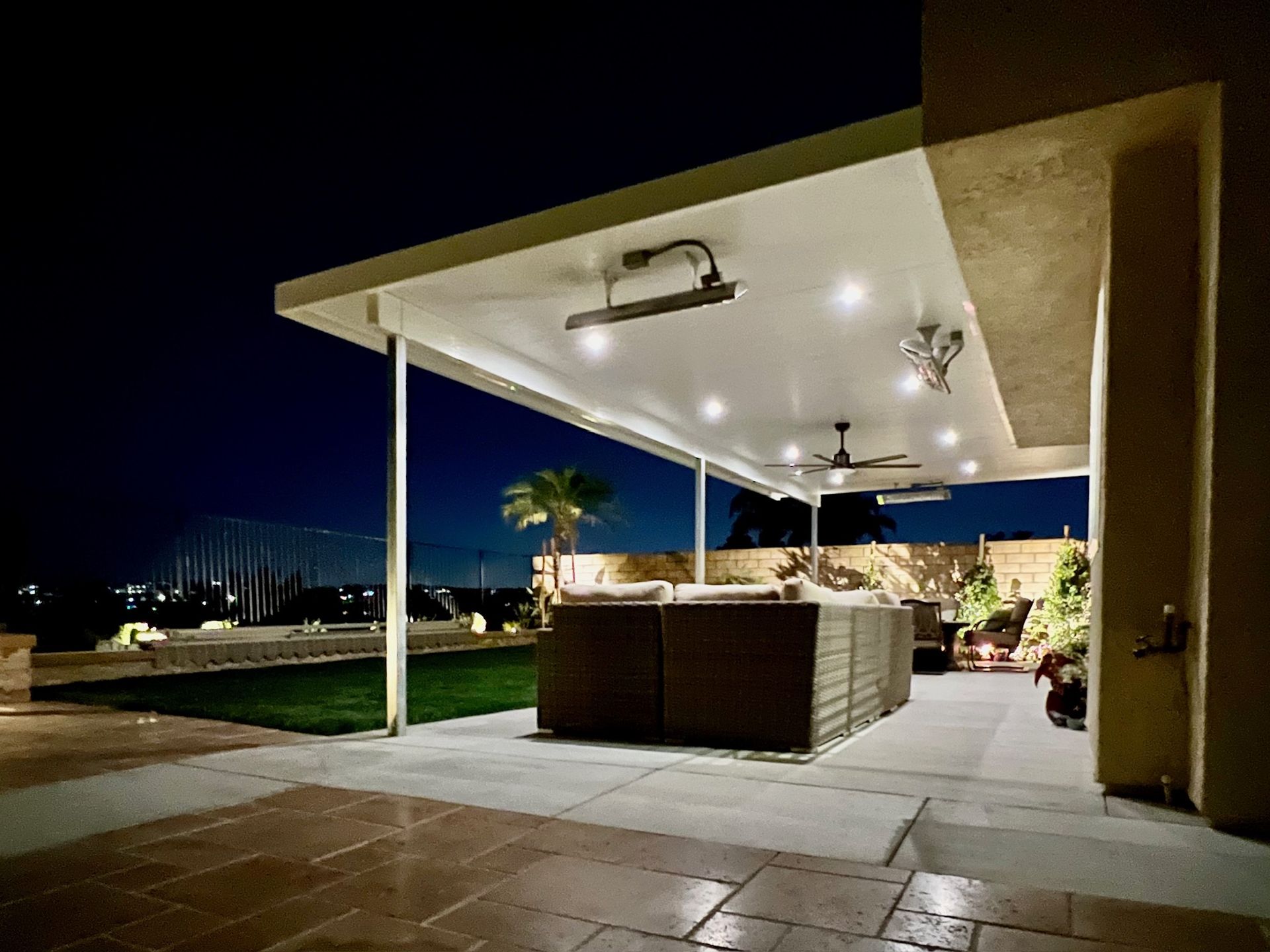 Outdoor patio at night with seating, lighting, and a view of a harbor.