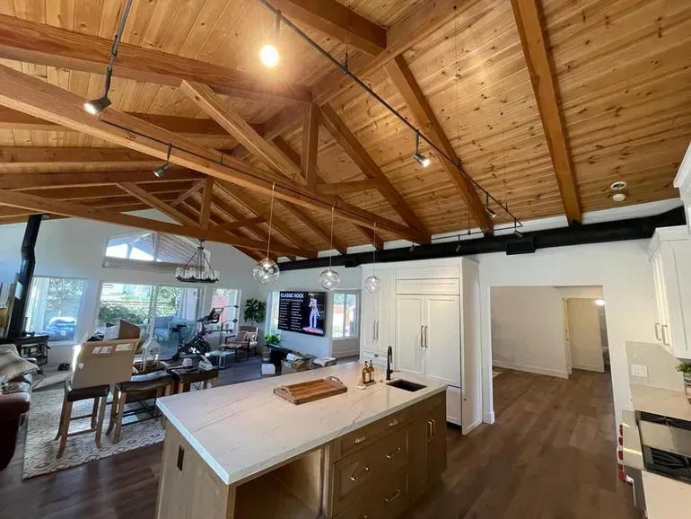 A kitchen with a wooden ceiling and a large island in the middle of the room.
