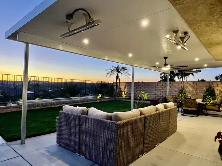 A patio with a couch and chairs under a covered patio with a ceiling fan.