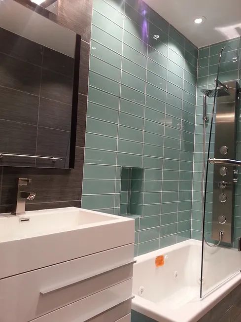 A bathroom with green tiles, a sink, and a bathtub.