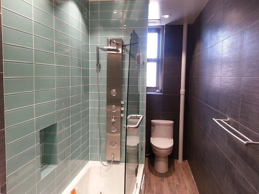 A bathroom with green tiles and a toilet