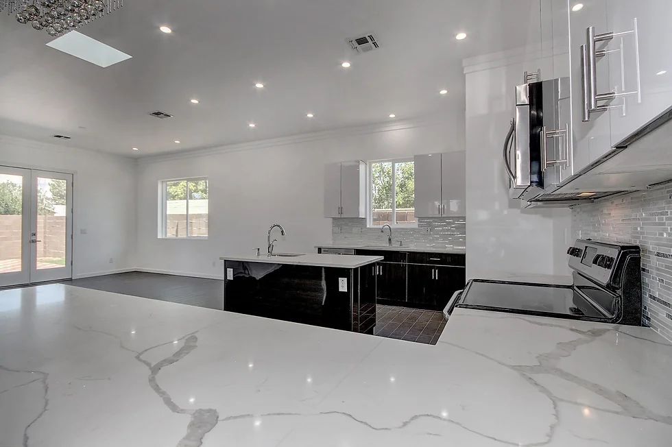 An empty kitchen with white cabinet, black appliances, and a marble counter top.