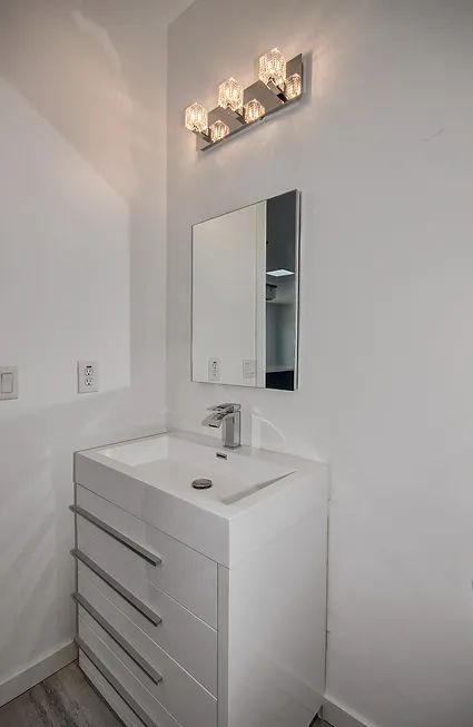 A bathroom with a sink, mirror and light fixture.