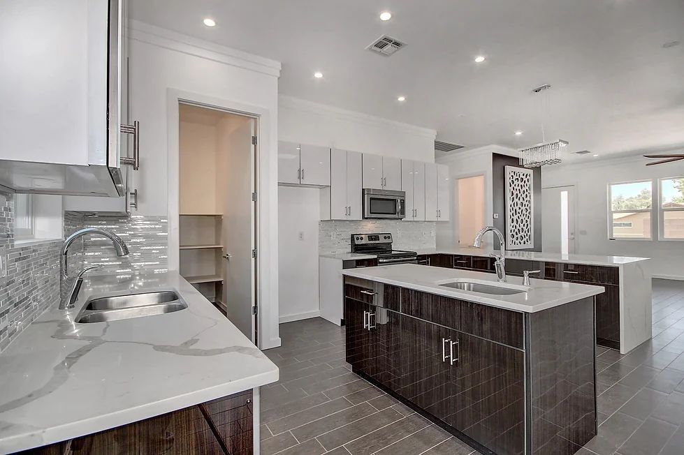 A kitchen with white cabinets and a large island in the middle.