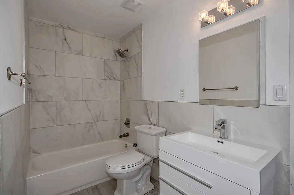 A bathroom with a toilet, sink, bathtub and mirror.