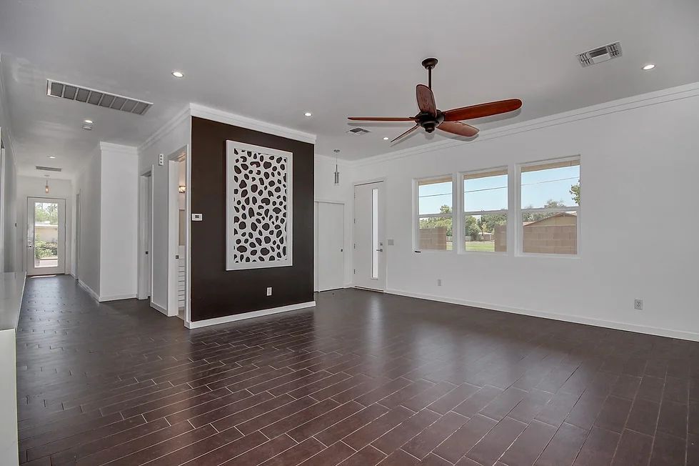 An empty living room with hardwood floors and a ceiling fan