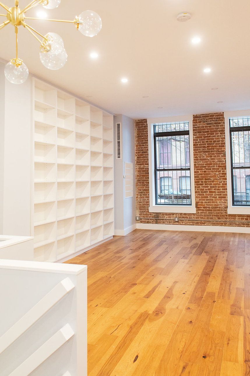 A living room with hardwood floors and a brick wall.