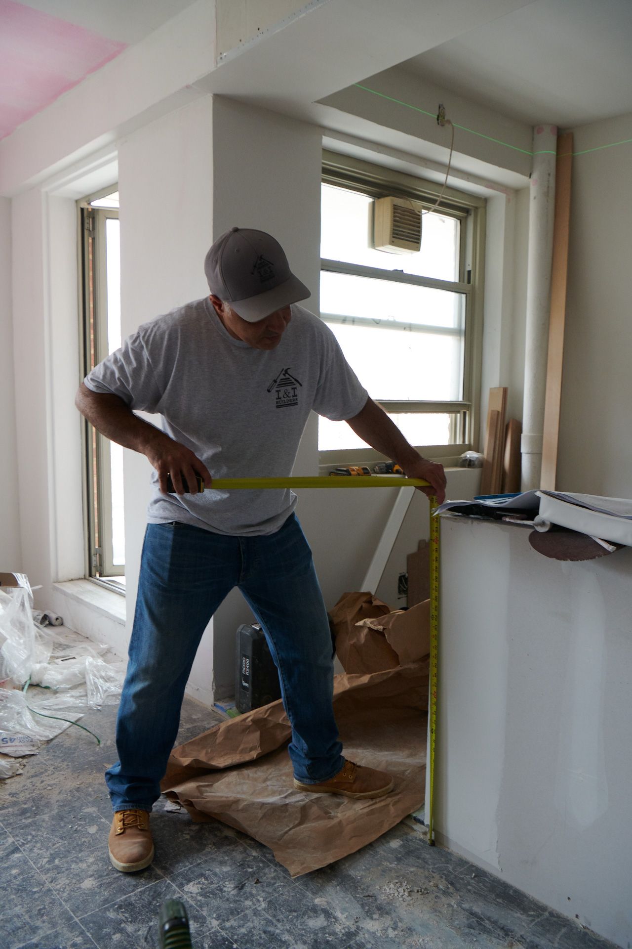 A man is measuring a wall with a tape measure.