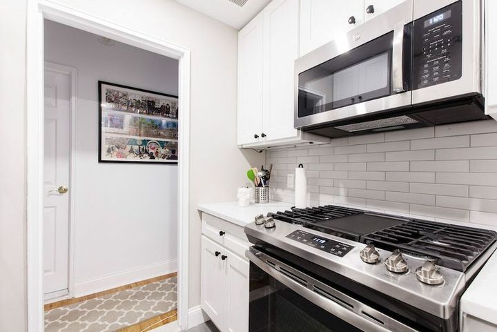 A kitchen with a stove, oven, microwave and white cabinets.